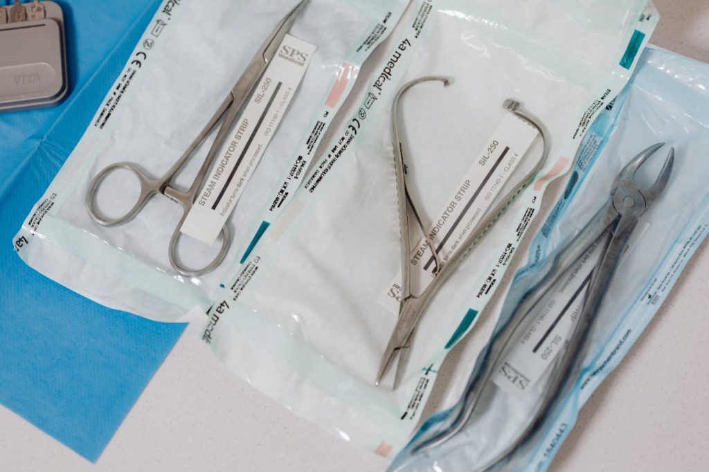 pexels-photo-6627704 Close-up of sterilized surgical tools in packaging on a clinical table.