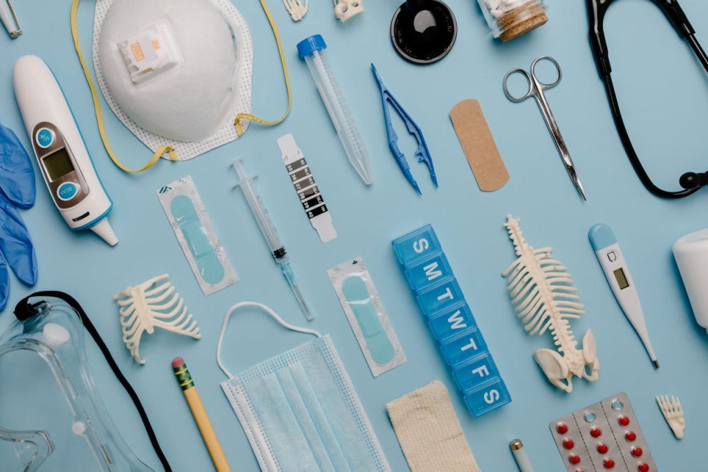 pexels-photo-7722927 A comprehensive flat lay of diverse medical supplies including PPE and diagnostic equipment on a blue surface.