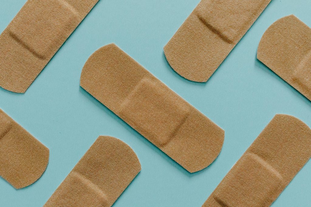 pexels-photo-7722865-7722865 A minimalist flat lay of adhesive bandages on a blue background, perfect for health and treatment themes.